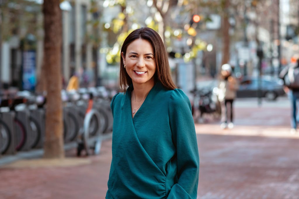 Staff member Katherine Georgiev wearing a teal shirt stands and smiles.