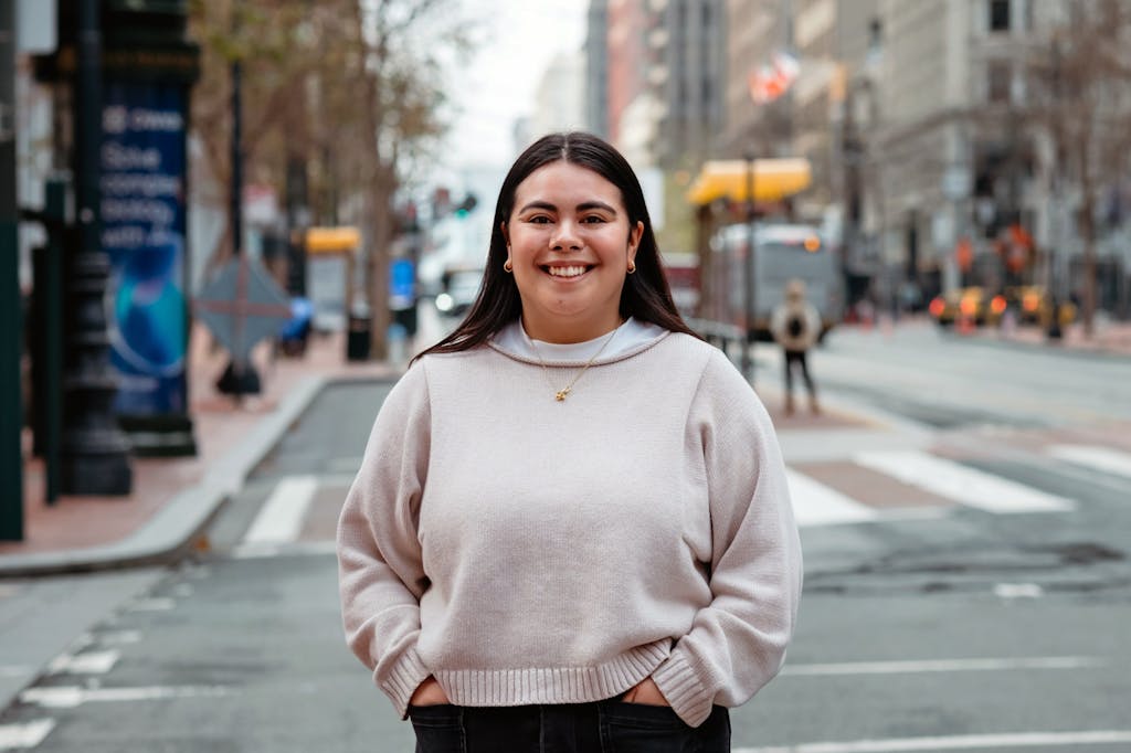 Staff member Marin Garcia wearing a beige sweater stands and smiles.